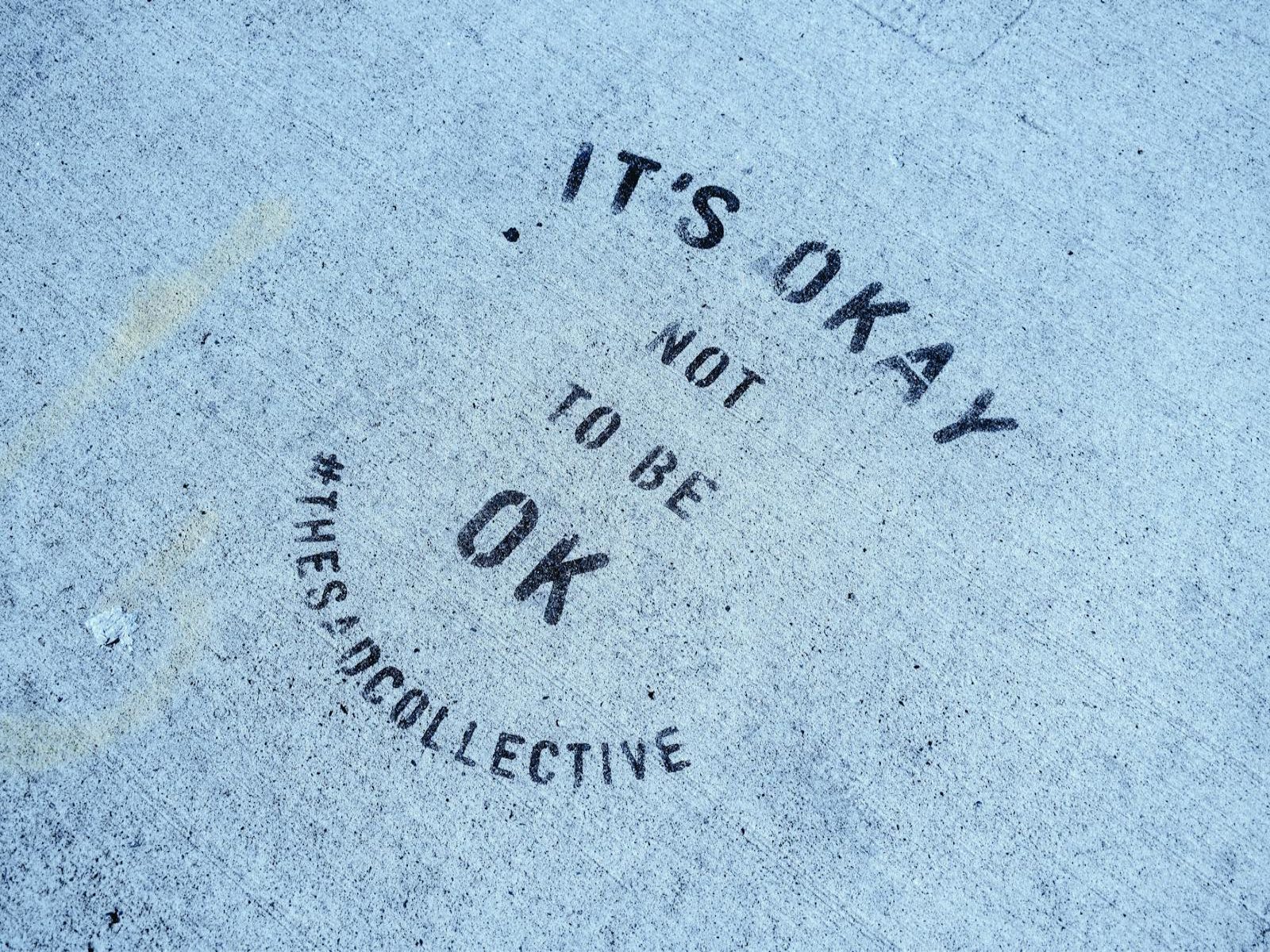 Close-up of 'It's Okay Not To Be Ok' message on Toronto pavement.