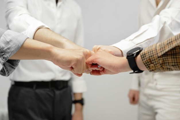 Close-up of diverse team members doing a fist bump indoors, symbolizing unity and teamwork.